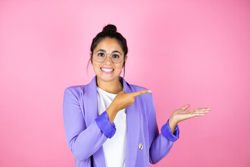 Young beautiful business woman over isolated pink background smiling, showing and pointing something that is on her hand