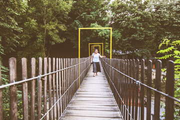 Woman crossing wooden suspension bridge