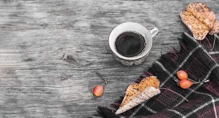 Autumn cozy composition. Cup of coffee, plaid, dried leaves on a wooden background. Autumn, fall concept. Flat lay, copy space, banner