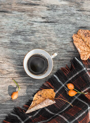 Autumn cozy composition. Cup of coffee, plaid, dried leaves on a wooden background. Autumn, fall concept. Flat lay, top view, copy space