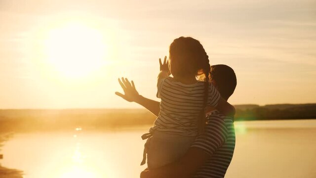 happy family dad and daughter by the sea at sunset silhouette. father and child kid reach out to the sun. kid a dream concept. happy family little girl and dad alone with nature sunset relax concept