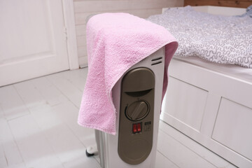 A dangerous hazardous situation with mobile oil heater covered with a towel, that is dryin on a hot...