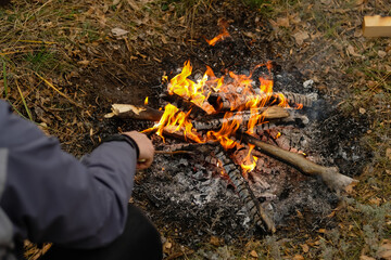 Camping with bonfire ash close up view. Man starts a fire.