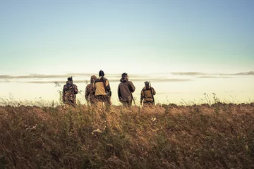 Foto op Aluminium Hunters silhouettes against sky going through rural field towards horizon during hunting season © splendens