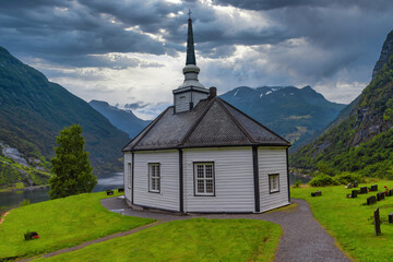 Fototapeta na wymiar Geiranger Church, on a hill overlooking the Geiranger Fjord, Norway. The white, wooden church was built in an octagonal style in 1842.