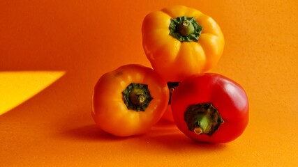 four yellow and red pepper on an orange background. harvest time. Levitating peppers