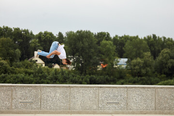 brave strong guy trains parkour while jump below sky. full length side eview photo. hobby, interests. copy space