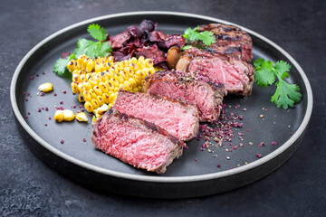 Barbecue dry aged wagyu roast beef steak with corn and vegetable chips offered as close-up on a modern design plate