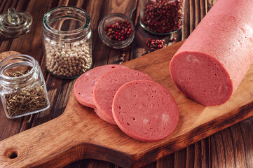 Sliced mortadella on a wood cutting board with spices