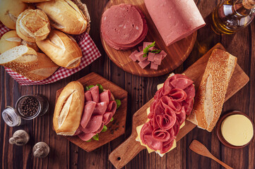 Mortadella sandwich on a wood cutting board with bread, butter and spices - Top view - obrazy, fototapety, plakaty