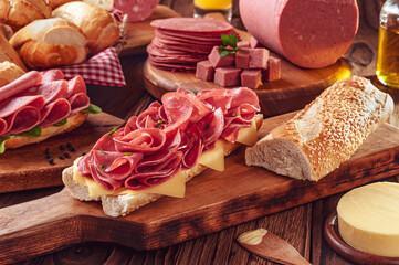 Mortadella sandwich with butter, bread and spices on wood cutting board