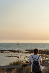 Fototapeta na wymiar : Mujer con mochila mirando un velero en el mar