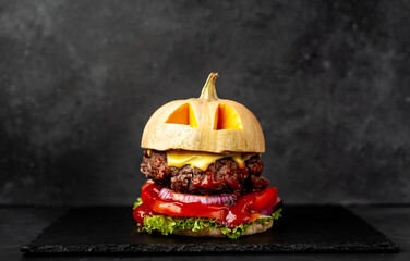 pumpkin-shaped burger for halloween holiday on stone background