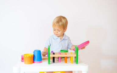Beautiful blond baby sitting and playing with his toys