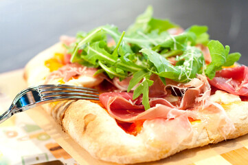 Pizza with tomato sauce, organic arugula, mozzarella cheese, Parma ham and parmesan cheese.
