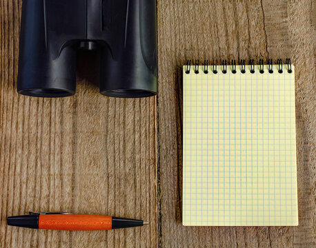 Yellow notebook, binoculars and pen. Birdwatching.