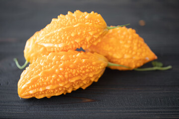 Momordica charantia on a wooden background. Ripe whole fruits of Momordica charantia, also known as bitter melon or bitter squash. Selective focus.