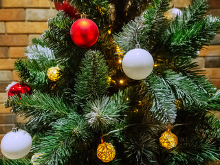 Fragment of a Christmas tree with red and white balls and a garland in the form of wicker balls with a light bulb inside