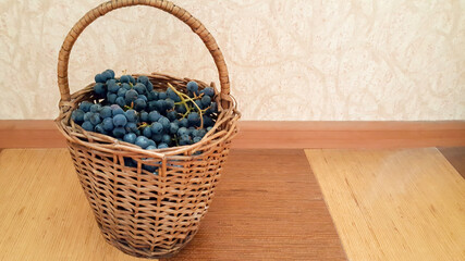 Fototapeta na wymiar Ripe blueberries in a wicker basket stands on the floor. Healthy eating concept.
