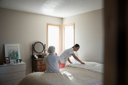 Senior Woman Watching Home Caregiver Making The Bed