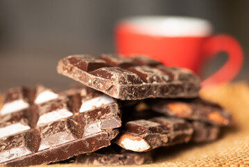 Broken chocolate pieces on wooden background. Selective focus.