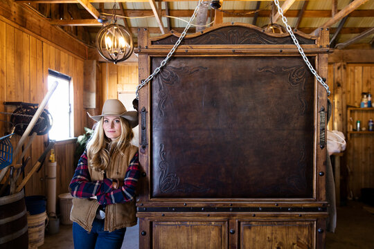 Portrait Confident Cowgirl Leaning On Wood Furniture In Barn