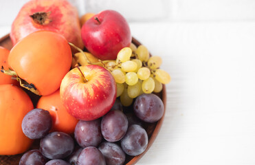 Autumn composition with fresh fruits. Apple, plum, melon, persimmon, pomegranate, grapes. Selective focus.
