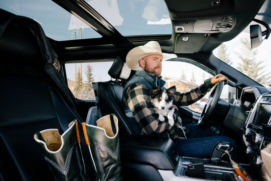 Cowboy Driving Truck With Dog In Lap