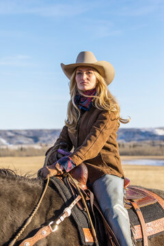 Portrait female rancher horseback riding on sunny ranch