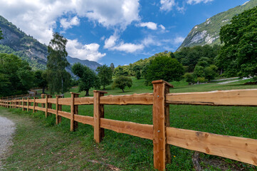 Fototapeta na wymiar Wooden fence with summer landscape in the mountains, clouds, blue sky near lake tenno, wine route, near Lake Garda, Riva del Garda, Trentino Alto Adige, Trento, Italy
