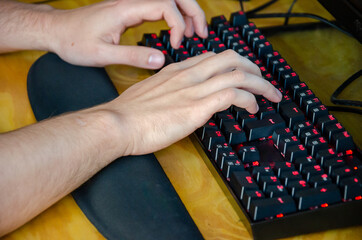 white male hands typing on keyboard with red light
