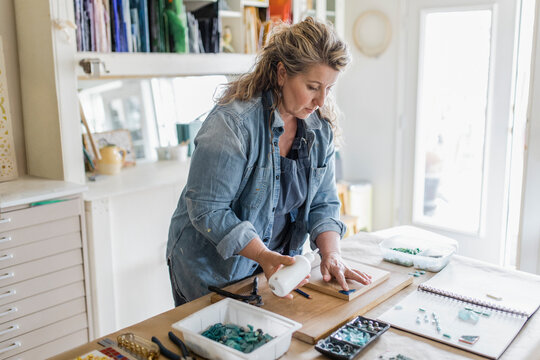 Female artist assembling mosaic art project in home studio