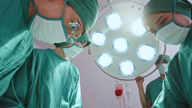 Group of Asian doctor, practitioner and nurse performing surgical operation in hospital's operating room, low angle view. Healthcare job, OR medical technology concept