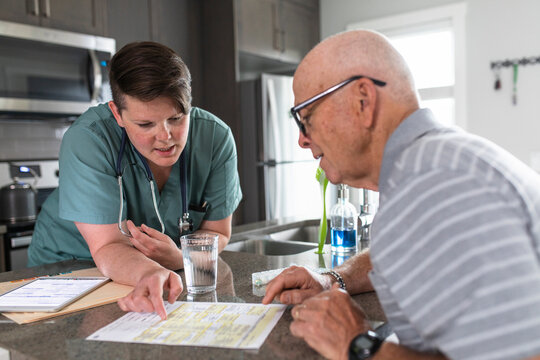 Home caregiver explaining test results with senior patient in kitchen