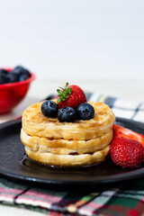 WAFFLES WITH STRAWBERRY BLUEBERRY AND SYRUP.