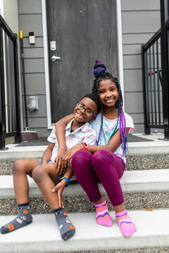 Portrait happy affectionate brother and sister on front stoop