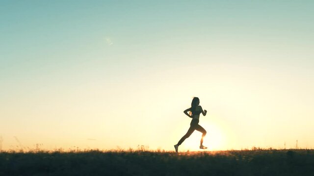 Free young woman runs in the summer park at sunset. A healthy beautiful girl is engaged in fitness, jogging in country in sun. training jogging. Jogger girl breathes fresh air. lsports lifestyle