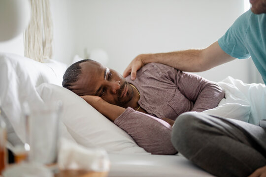 Gay man caring for sick boyfriend resting in bed