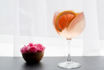 still life with a rose cocktail with grapefruit in a glass of wine, dreamy background pink pastel tone