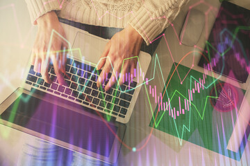 Double exposure of woman hands working on computer and forex chart hologram drawing. Top View. Financial analysis concept.