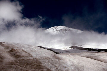 Climbing Elbrus. Snow-capped mountain peaks and figures of climbers in the foreground. Mountains covered with snow.