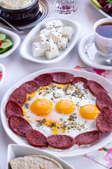Traditional Turkish Breakfast with tomato,olives,honey,tea,cheese and egg with sausage on white surface.