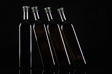 Dark bottles with edible oil. Utensils for the storage of light-sensitive food. Dark background.