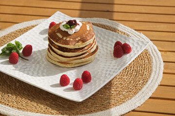 vanilla pancakes on a white plate with raspberries