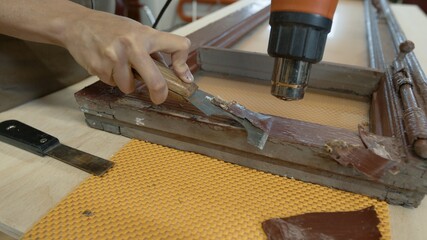 Restoration of wooden doors, window. A working female carpenter peels off paint from a wooden product with a spatula and a heat gun
