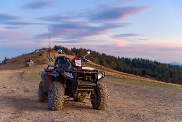 Fototapeta premium ATV on the mountain top at summer sunset background. Travel and extreme tourism concept.