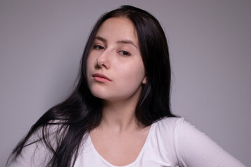 Obraz premium Close up portrait of pretty confident pensive thoughtful girl, looking seriously brunette. on grey background with copy space. People lifestyle concept