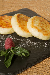 vanilla cheesecakes (cottage cheese pancakes) poured with honey on a black plate