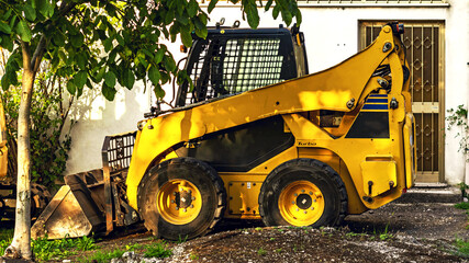 earth mover industrial vehicle parked in the shade of a walnut tree