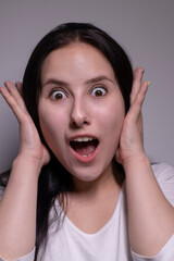 Young suprised brunette woman, isolated on gray background. happy girl actress portrait. The human emotions, facial expression concept